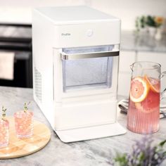 a white machine sitting on top of a counter next to two glasses filled with drinks