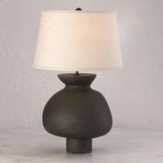 a black table lamp with a white shade on the base and a beige linen lampshade