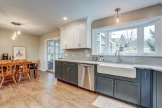 Kitchen remodel with white upper cabinets, a grey backsplash, light granite countertops, new vinyl plank flooring, and farm sink under the bay window Azul Celeste Granite Countertops, Stainless Steel Apron Sink With Dark Cabinets, Sensa Silver Blue Granite