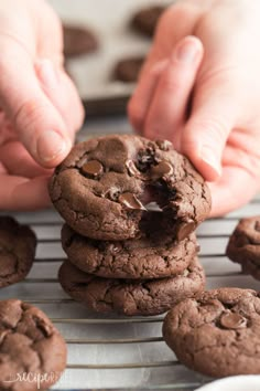 someone picking up a chocolate cookie from a cooling rack