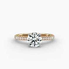 a round brilliant cut diamond engagement ring with pave set shoulders and side stones in yellow gold