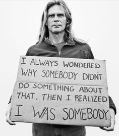 a man holding a sign that says i was somebody and it is written on it