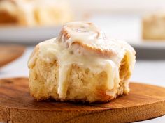 a cinnamon roll with icing sitting on top of a wooden board