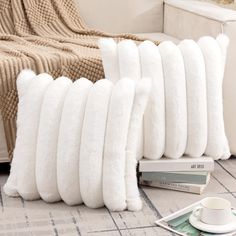 a stack of white pillows sitting on top of a floor next to a coffee cup