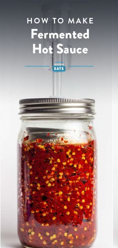 a jar filled with hot sauce sitting on top of a table