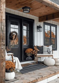 a porch decorated for fall with pumpkins and mumbers