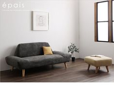 a living room with a gray couch and wooden flooring next to a small plant