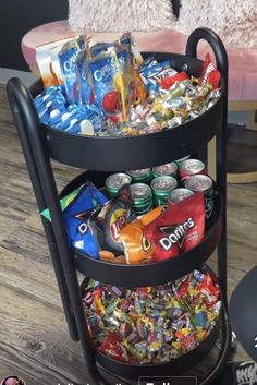 a three tiered tray with drinks and snacks on the bottom is sitting on a wooden floor