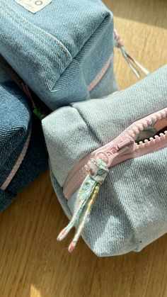 three pieces of blue jeans with zippers on them sitting on a wooden table next to each other