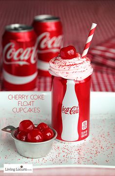 two cans of coca - cola and a bowl of cherries on a tray with red sprinkles