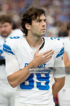 a football player standing on the sidelines with his hands clasped