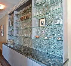 a wall with glass shelves and vases on it