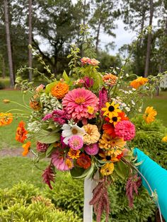 a bouquet of flowers sitting on top of a white pole in front of some bushes