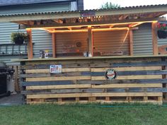 an outdoor bar made out of pallets and wooden planks with lights on top