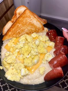 a black plate topped with eggs, sausages and toast