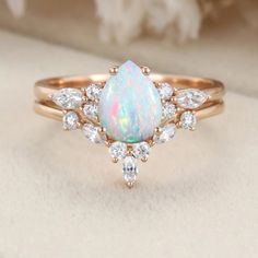 a white opal and diamond ring sitting on top of a table