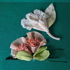 two paper flowers sitting on top of a green surface