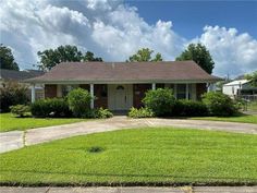 a house that has grass in front of it and bushes on the lawn behind it