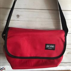 a red bag sitting on top of a white wooden floor next to a black strap