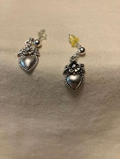 These dainty silver tone earrings consist of a 4mm ball post insertion stud with a little, one-sided 3D charm dangle. The charm shows a simple flower with a small heart below it. The earrings measure approximately 1 inch in length and come with butterfly backs. You can choose to add a drawstring gift bag for $1 in the dropdown.  Disclaimer: all measurements are approximate, as I only have a tactile tape measure that measures in half inches. Shades may vary based on lighting and your monitor. Colors were chosen with the assistance of friends and family or based on the description of the materials I bought. If you have an idea or request for a custom design, I will do my best to find materials and create your perfect item. I try to be accurate when listing my materials but I make no promises Trendy Drop Earrings For Valentine's Day, Trendy Valentine's Day Drop Earrings, Trendy Sterling Silver Jewelry For Mother's Day, Minimalist Heart Charm Dangle Jewelry, Heart Charm Dangle Jewelry For Gifts, Pierced Metal Heart Pendant Jewelry, Delicate Dangle Heart Charm Jewelry, Heart Charm Drop Earrings Jewelry For Gift, Pierced Heart Pendant Jewelry