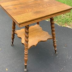 an old wooden table sitting in the middle of a street with grass behind it and a sidewalk