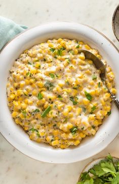 a white bowl filled with corn on top of a table