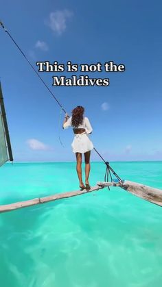 a woman standing on the end of a boat holding onto a fishing pole while looking out at the ocean