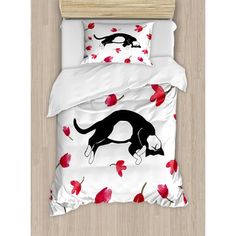 a bed with red flowers and a black dog on it