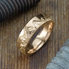 a gold wedding ring sitting on top of a wooden table