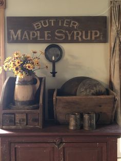 an old wooden cabinet with flowers and other items on it in front of a sign that says butter maple syrup