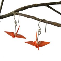 two orange origami birds hanging from long silver ear wires on a tree branch