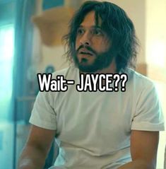 a man with long hair and beard sitting in front of a glass door that says wait - jayce?