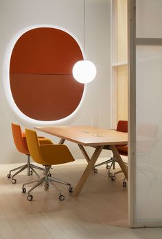 a table with chairs and a round light hanging from it's side in an office