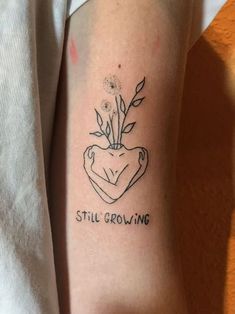 a person with a tattoo on their arm that says still growing and a flower in the center