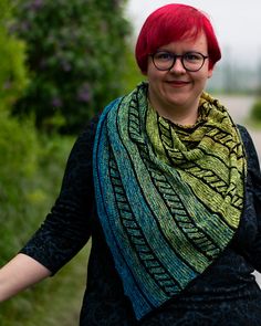 a woman with red hair and glasses is wearing a green, blue, and yellow shawl