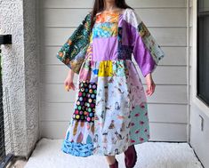 a woman standing in front of a door wearing a colorful dress with patches on it