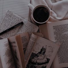 an open book sitting on top of a pile of books next to a cup of coffee