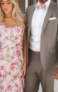 a man in a suit and tie standing next to a woman wearing a floral dress