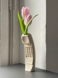 a phone shaped vase with pink flowers in it