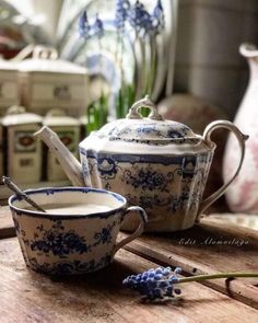 a tea pot and cup sitting on top of a wooden table next to each other