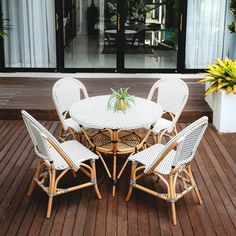 an outdoor table and chairs on a deck with potted plants in the background,