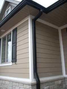 the side of a house with a black gutter hose attached to it