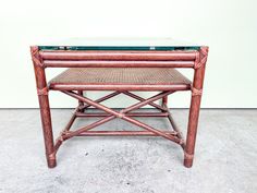 a table with a glass top and wooden frame on the bottom, sitting against a wall