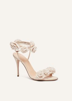 a women's white high heeled sandal with flower decoration on the ankle