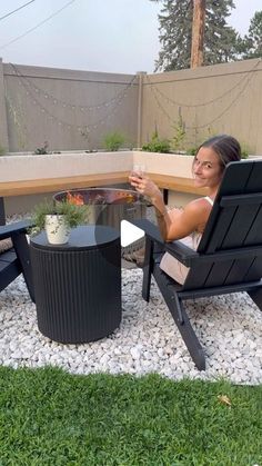 a woman sitting in a chair on top of a gravel covered ground next to a table