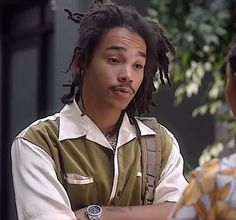 a young man with dreadlocks standing next to another person