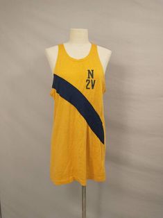 "From the estate of a collegiate crew member this is a 1970's athletic tank top jersey. Could have been for rowing or track, any sport a tank was appropriate for. Color is sunflower yellow - gold with navy blue stripe and lettering. Letters are N 2V, stripe is sewn on. Light/mid weight knit, label missing, likely made in USA. No size marked. Overall condition good, seems to have aged with a very slight diagonal twist. Some light marks on left shoulder and left side back. Has stretch, measurement Cotton Activewear With Three Stripes For Sports Events, Collegiate Sleeveless Cotton Top, Cotton Workout Tops With Three Stripes, Retro Tops For Sports Events In Summer, Collegiate Cotton Sleeveless Tank Top, Retro Tops For Summer Sports Events, Collegiate Sleeveless Cotton Tank Top, Sporty Tank Top For College In Summer, Retro Summer Tops For Sports Events