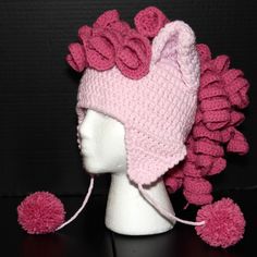 a crocheted pink hat with pom - poms