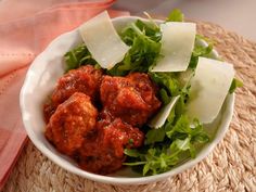 a white bowl filled with meatballs and lettuce on top of a table