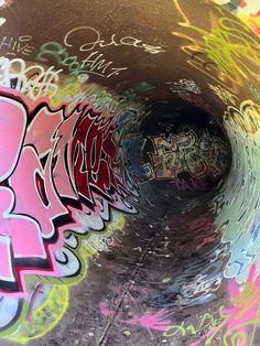 graffiti is painted on the side of a pipe in an underground tunnel that's filled with spray paint